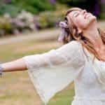 A woman in a park, open and receptive to receive energy through EFT tapping.